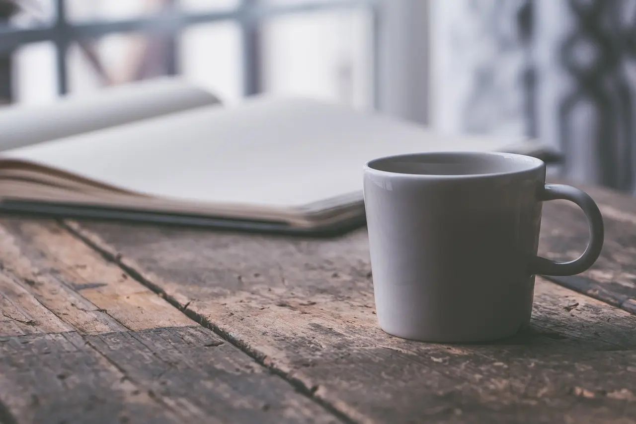 Kaffekop og notesbog i roligt morgenlys